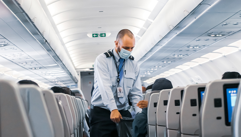 Man standing in aisle of airplane with mask on