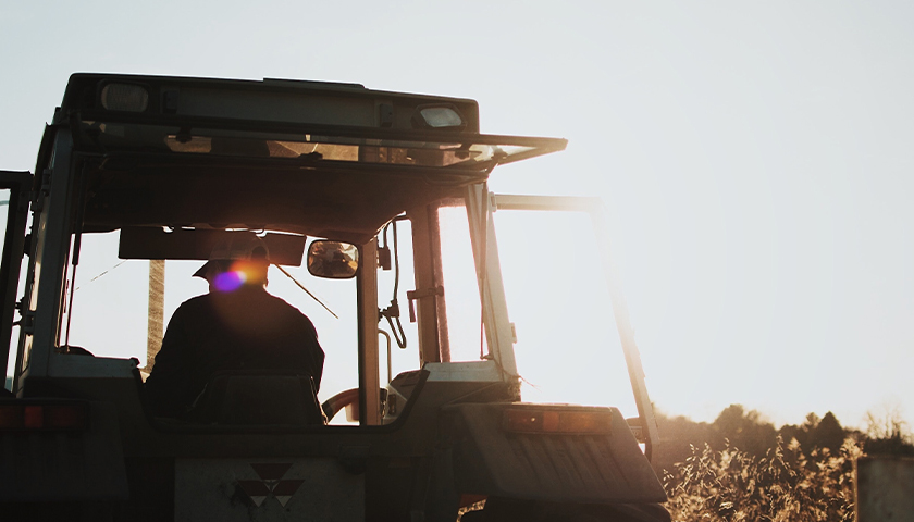Silhouette of man on a tractor during golden hour